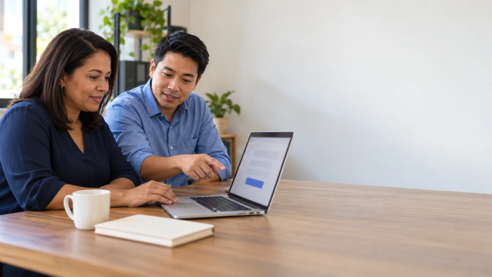Dona de pequena empresa revisa o formulário de contato do site no notebook com um colega em escritório iluminado